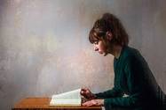 Frau sitzt am Tisch und liest ein Buch
